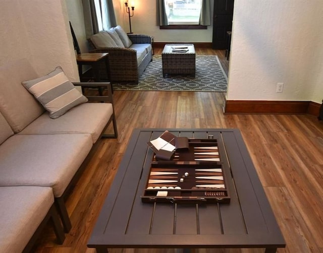 living room with wood finished floors, a textured wall, and baseboards