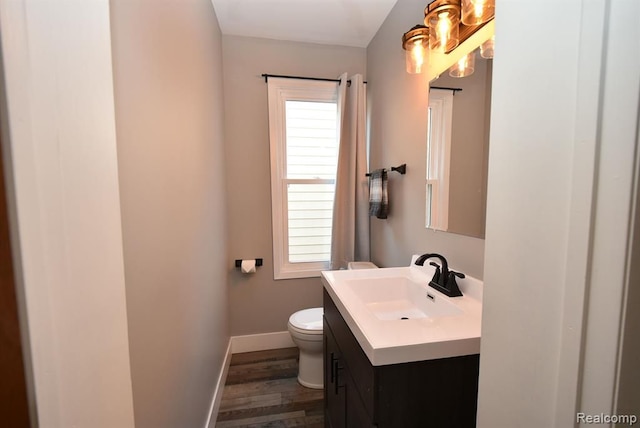 bathroom featuring toilet, vanity, wood finished floors, and baseboards