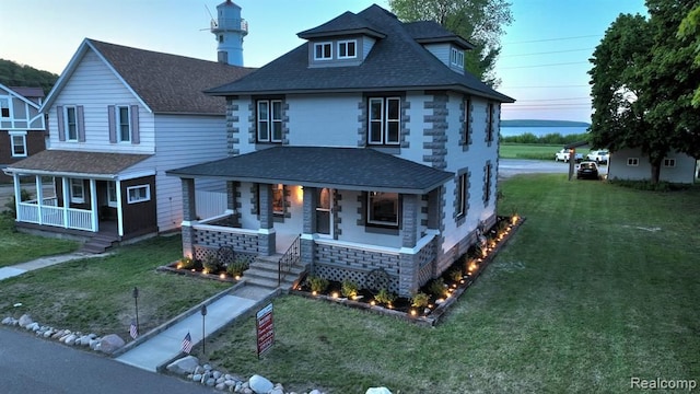 view of front facade featuring a front yard, a porch, and a shingled roof