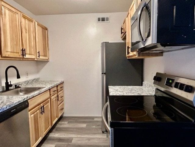 8741 Green Willow St Unit 11, Brighton, MI 48116 - kitchen featuring appliances with stainless steel finishes, a sink, light brown cabinetry, wood finished floors, and light countertops