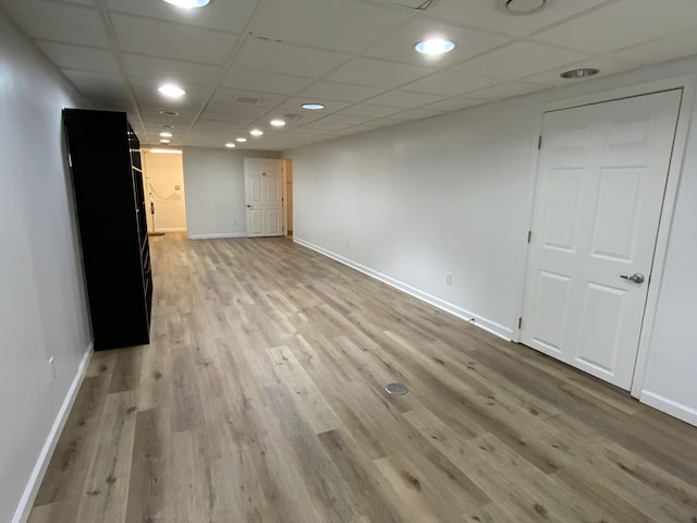 finished below grade area featuring baseboards, light wood finished floors, a paneled ceiling, and recessed lighting