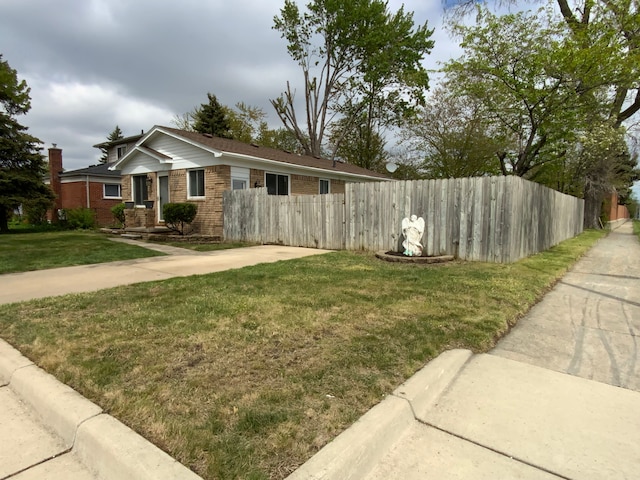 view of side of home with a lawn, brick siding, and fence