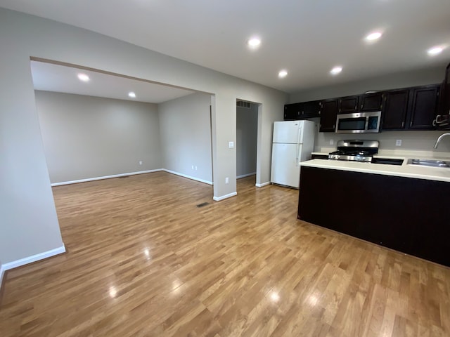 kitchen featuring freestanding refrigerator, stove, dark cabinets, stainless steel microwave, and light countertops
