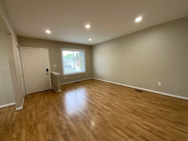 empty room with recessed lighting, baseboards, visible vents, and wood finished floors
