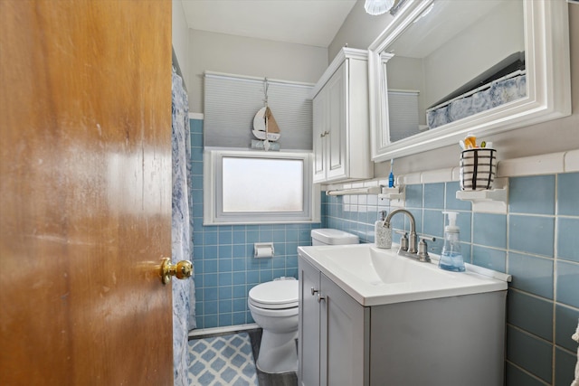 full bathroom featuring toilet, vanity, tile patterned flooring, and tile walls