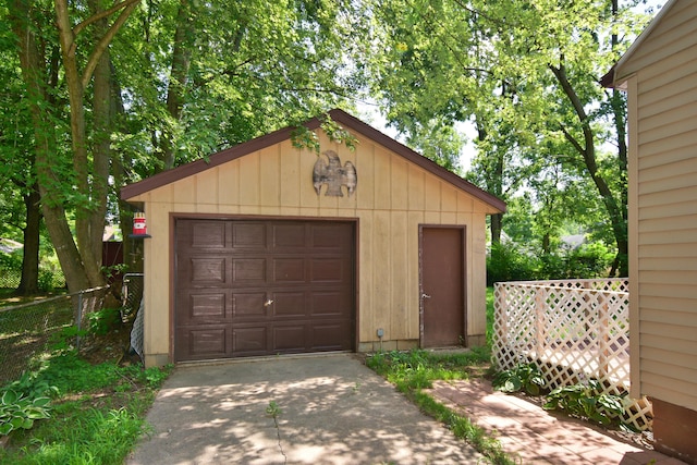 detached garage featuring fence and driveway