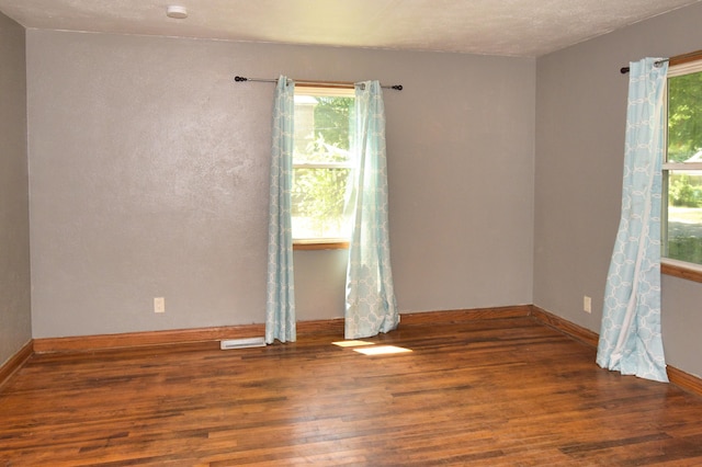 unfurnished room featuring wood finished floors, baseboards, and a wealth of natural light