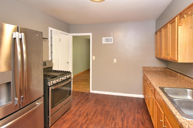 kitchen with visible vents, baseboards, a sink, appliances with stainless steel finishes, and dark wood finished floors