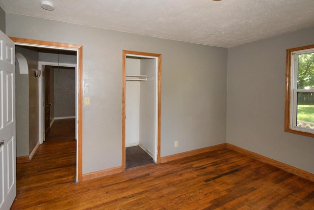unfurnished bedroom with a closet, baseboards, wood finished floors, and a textured ceiling