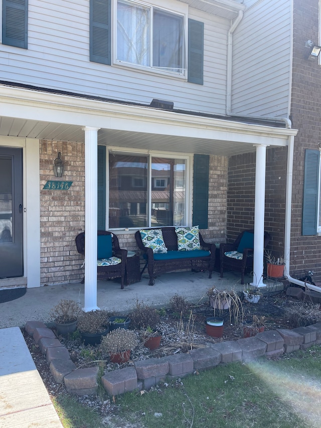 entrance to property featuring covered porch and brick siding