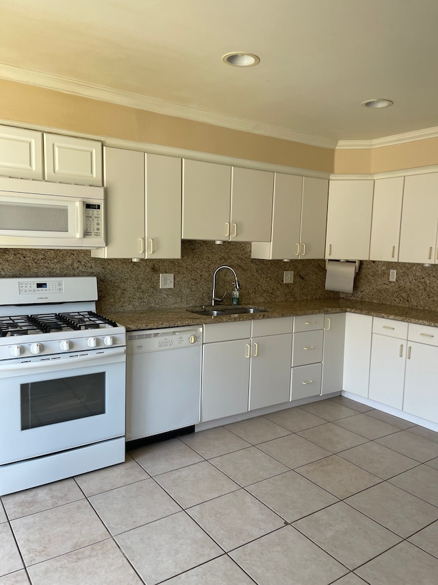 kitchen with backsplash, ornamental molding, a sink, white appliances, and dark stone counters