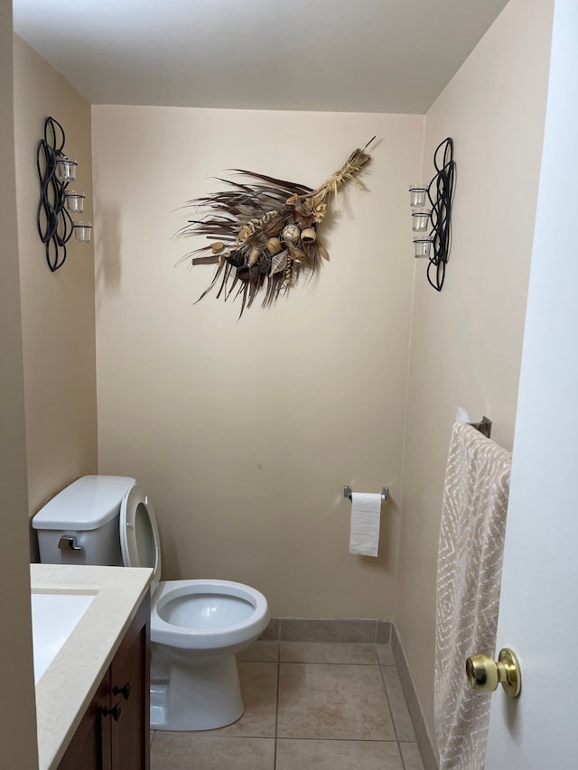 half bathroom featuring tile patterned floors, baseboards, vanity, and toilet