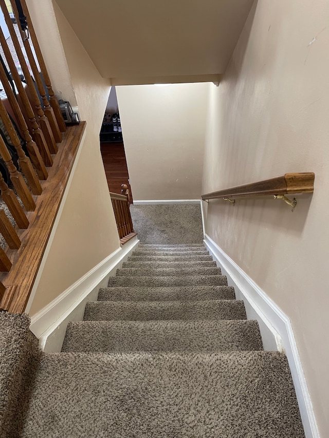 staircase featuring baseboards and carpet
