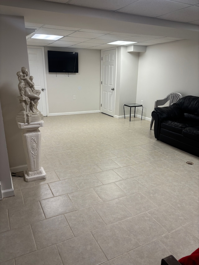 finished below grade area with tile patterned flooring, a drop ceiling, and baseboards