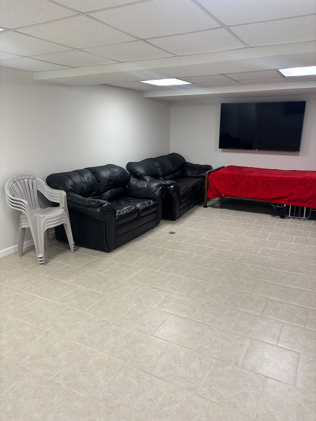 living area with a drop ceiling and baseboards