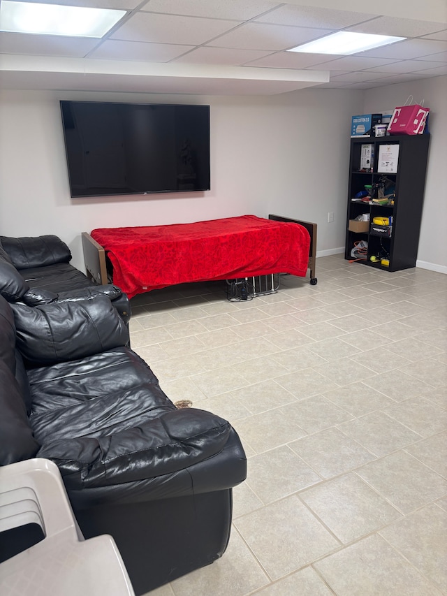 tiled living area with baseboards and a drop ceiling