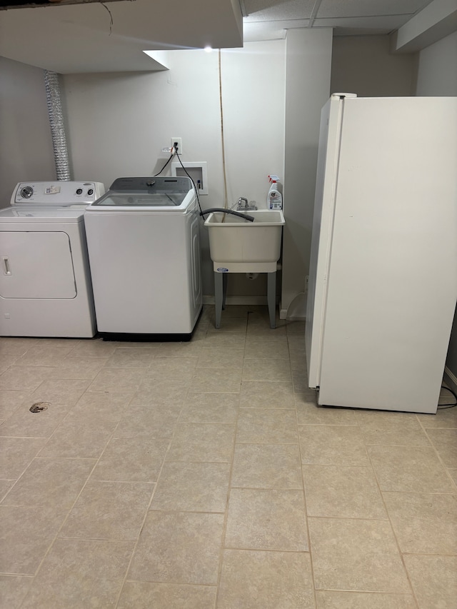 laundry area featuring laundry area, light tile patterned floors, a sink, and washer and clothes dryer