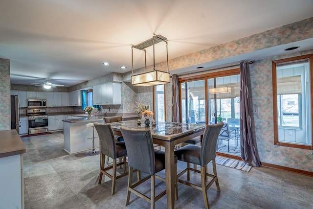 dining area with wallpapered walls, baseboards, and a healthy amount of sunlight