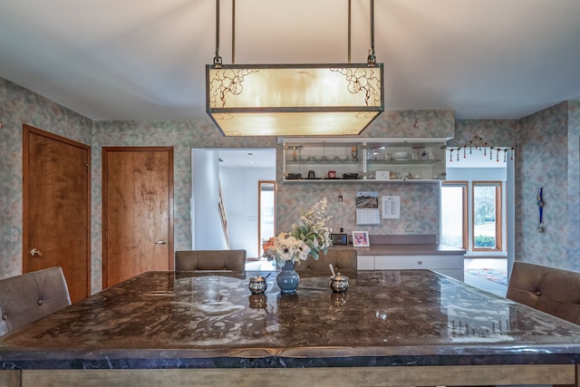 kitchen with open shelves, wallpapered walls, plenty of natural light, and dark stone countertops