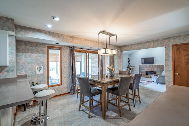 dining area featuring baseboards, a tile fireplace, and wallpapered walls
