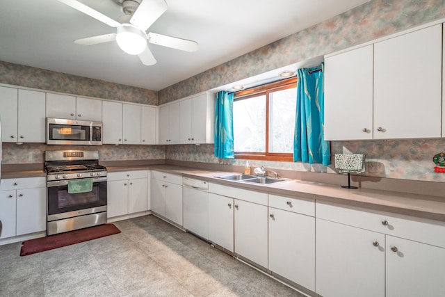 kitchen with stainless steel appliances, a sink, white cabinetry, a ceiling fan, and light countertops