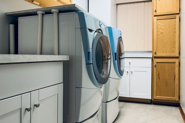 clothes washing area featuring washing machine and clothes dryer and cabinet space