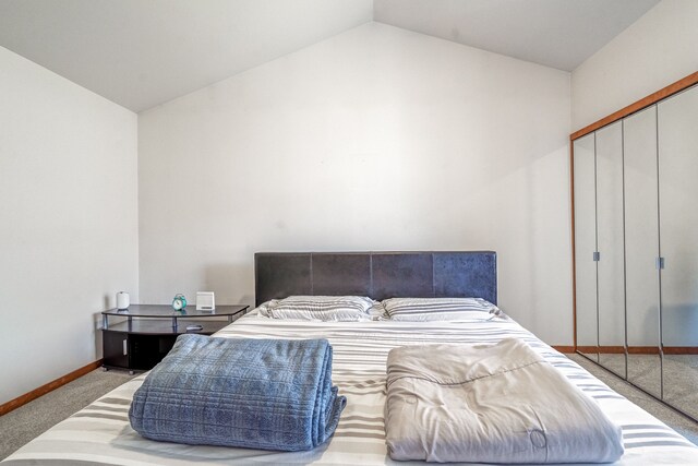 bedroom with baseboards, vaulted ceiling, carpet flooring, and a closet