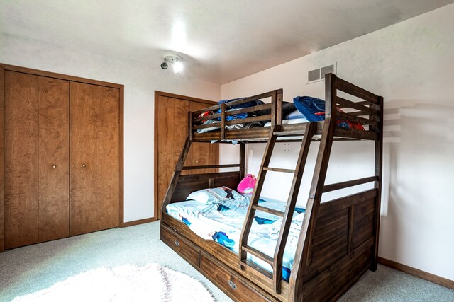 bedroom with baseboards, visible vents, and carpet
