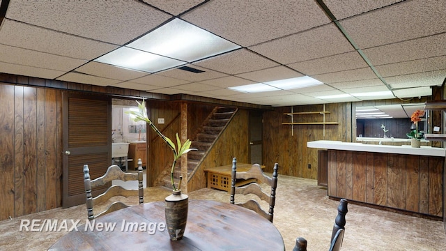 interior space with wood walls, carpet flooring, bar area, and stairs
