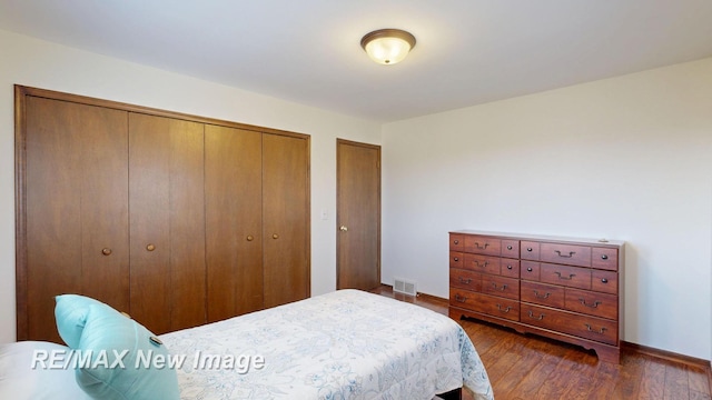 bedroom with visible vents, baseboards, multiple closets, and dark wood finished floors