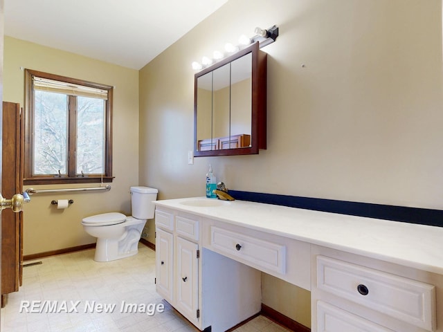 bathroom featuring toilet, baseboards, and vanity