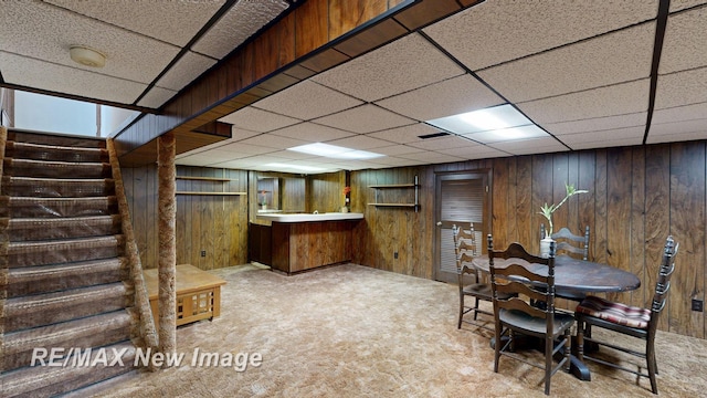 finished below grade area featuring stairway, a paneled ceiling, carpet, and bar area