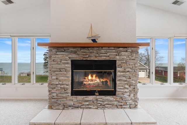 details with a stone fireplace, visible vents, carpet, and a water view