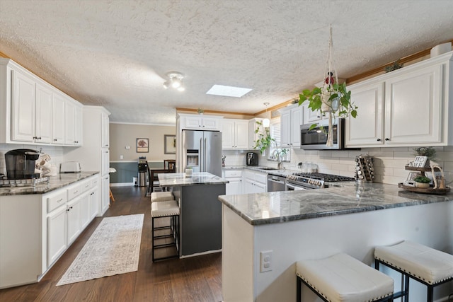 kitchen with appliances with stainless steel finishes, a breakfast bar, dark wood-style floors, backsplash, and stone countertops