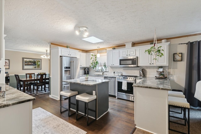 kitchen with white cabinetry, crown molding, backsplash, a breakfast bar area, and stainless steel appliances