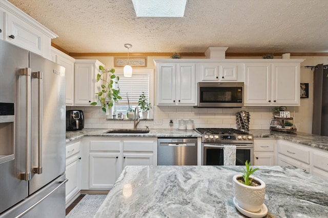 kitchen with white cabinetry, light stone counters, a sink, stainless steel appliances, and backsplash