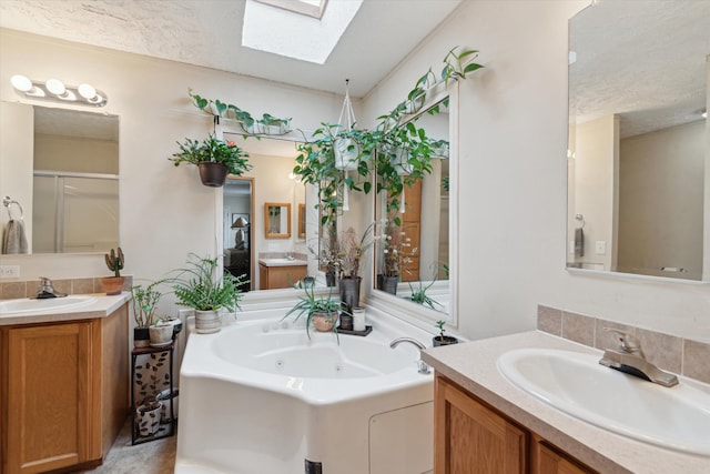 full bathroom featuring a whirlpool tub, a textured ceiling, a sink, and a skylight