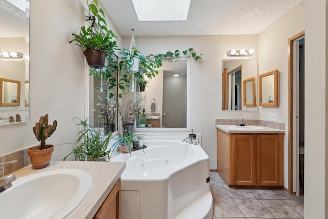 full bathroom featuring two vanities, a bath, a sink, and a skylight
