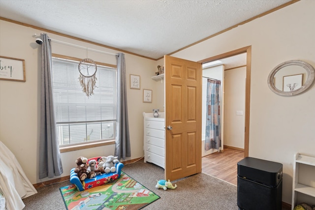 playroom with a textured ceiling, ornamental molding, and light carpet