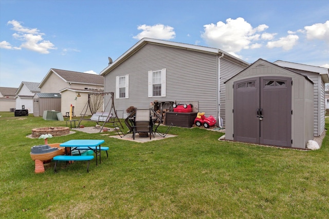 back of house with a fire pit, a patio area, a storage shed, an outbuilding, and a lawn