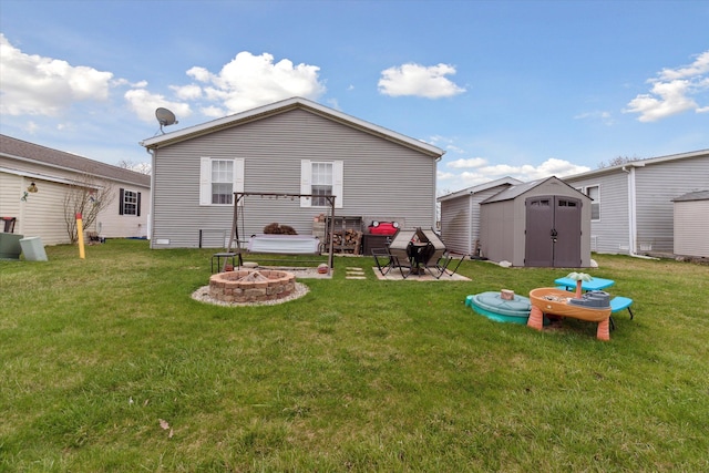 back of house with a shed, an outbuilding, an outdoor fire pit, and a lawn