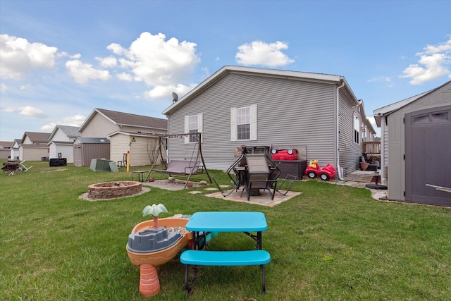 back of house with a yard, a fire pit, a storage shed, and an outdoor structure