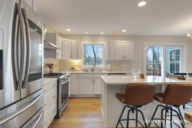 kitchen featuring a kitchen bar, recessed lighting, a sink, and stainless steel appliances
