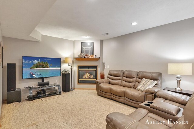 carpeted living room featuring a glass covered fireplace, recessed lighting, and visible vents