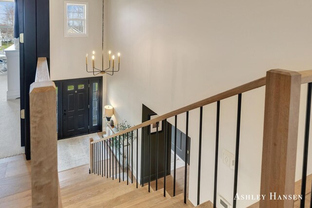 stairs with plenty of natural light, a chandelier, and wood finished floors