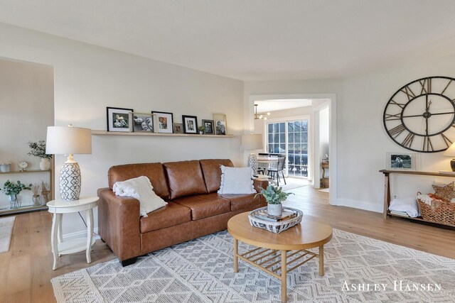 living room with a notable chandelier, baseboards, and wood finished floors