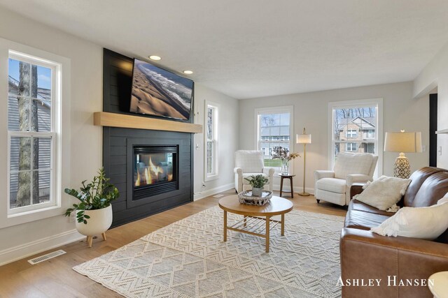 living room with visible vents, a large fireplace, baseboards, and wood finished floors