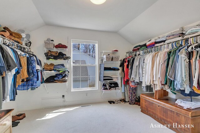 walk in closet with visible vents, carpet, and lofted ceiling