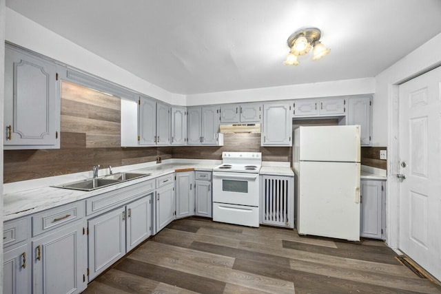 kitchen with a sink, light countertops, white appliances, dark wood-style floors, and under cabinet range hood