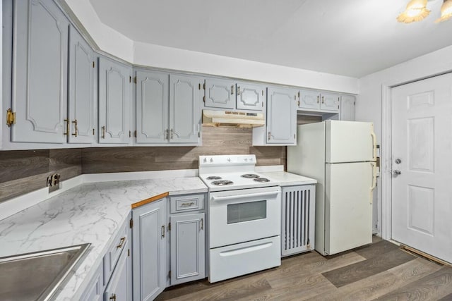 kitchen with dark wood-style flooring, white appliances, light countertops, under cabinet range hood, and a sink